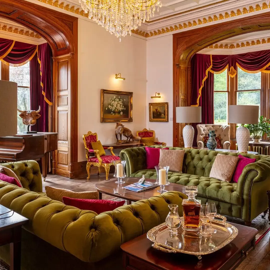 Rothes Glen luxury lounge area designed with green sofa's and contrast pink pillow underneath a chandelier with a side table of Scotch whiskey, Scotland