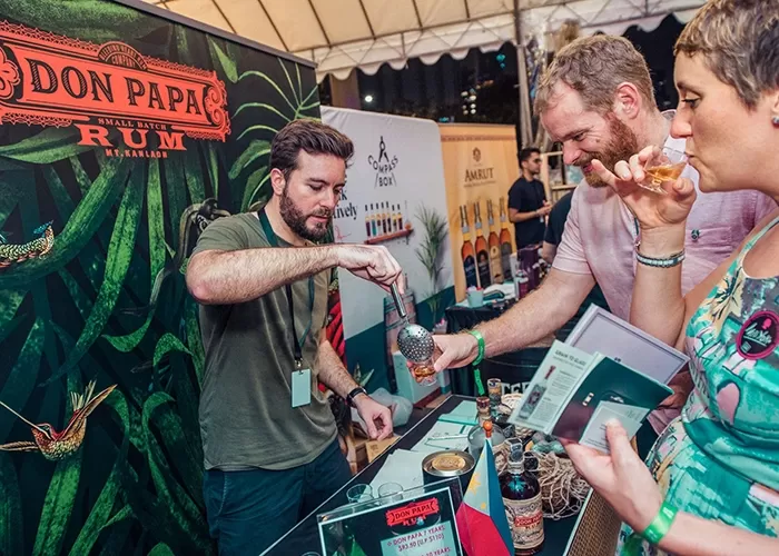 Man on cocktail stand pouring drinks for guests at the Singapore Cocktail Festival