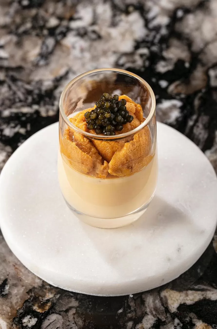 Uni Chawanmushi with caviar served in glass on coaster and marbled table at Shinji's, Flatiron, New York