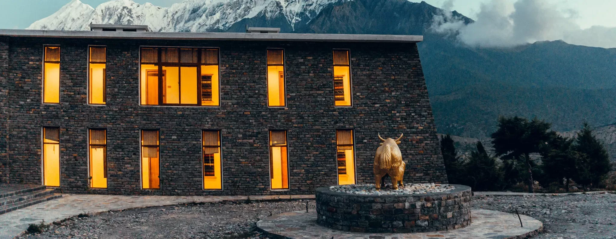 Exterior of stone building in front of snowy mountains at Shinta Mani Mustang, Nepal