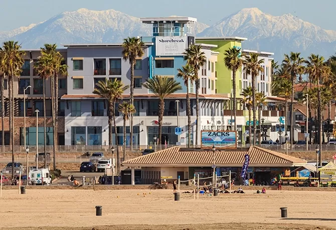 View of Shorebreak boutique resort hotel in front of tall mountains from Huntington Beach, California, USA