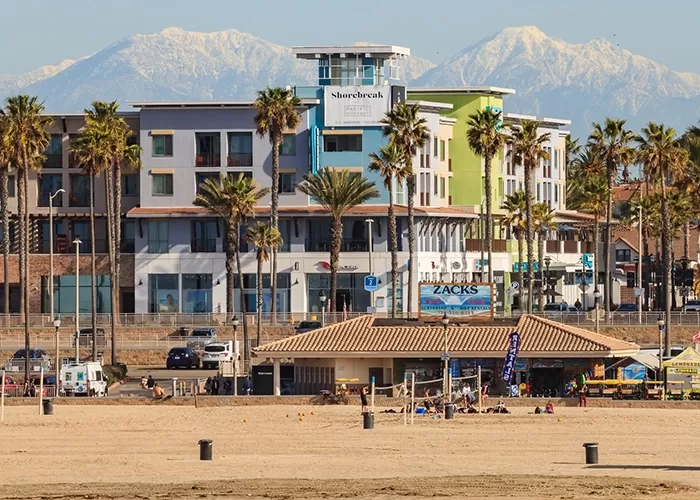 View of Shorebreak boutique resort hotel in front of tall mountains from Huntington Beach, California, USA