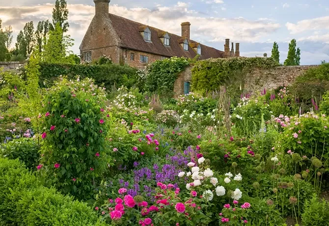 Countryside gardens filled with flowers outside an old brick house at Sissinghurst Castle Garden, Kent