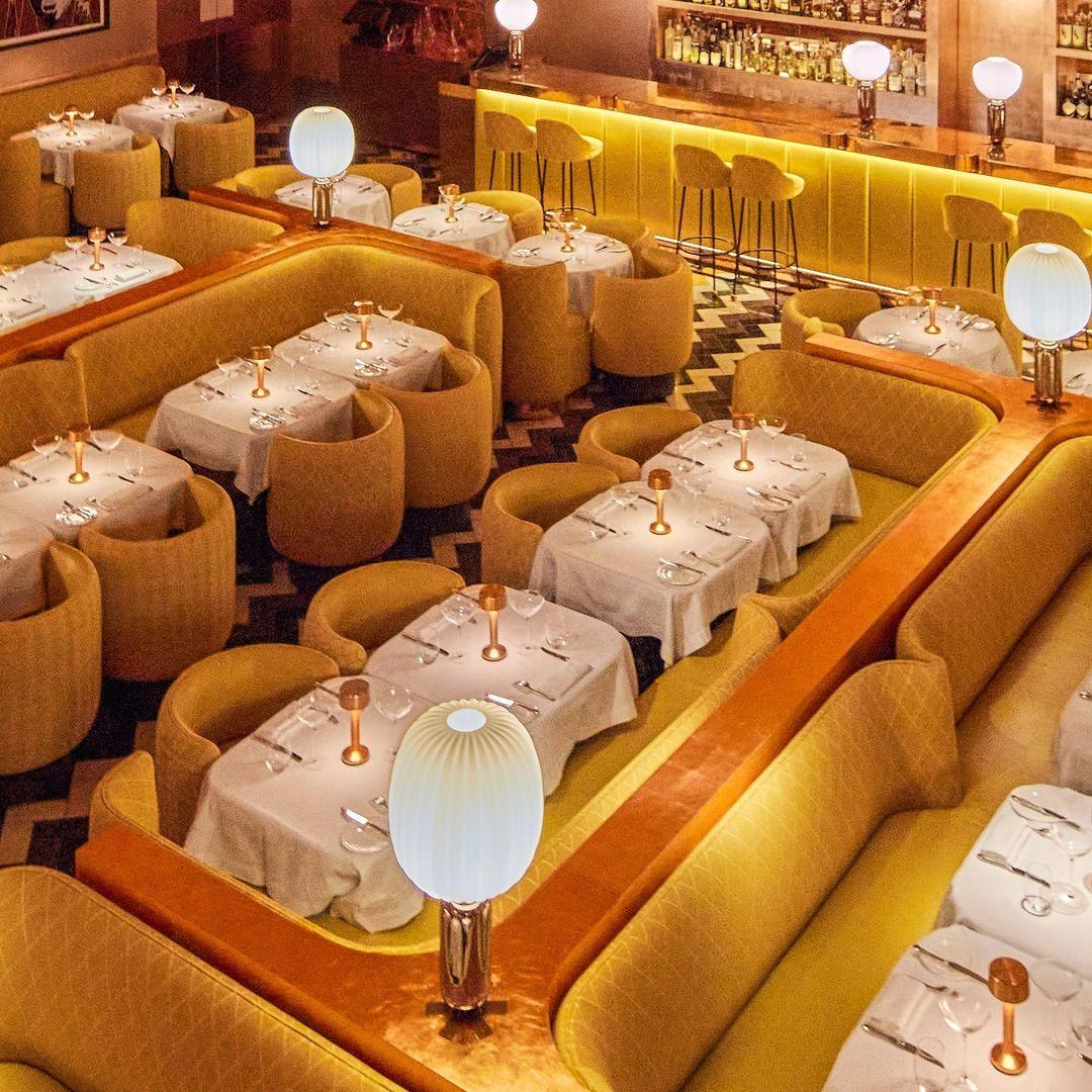 Birdseye view of yellow sofa and yellow rounded dining chairs with small white tables set up in rows in restaurant