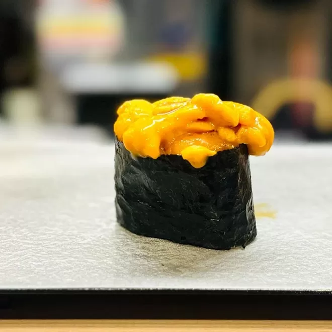 Black sushi roll with yellow topping