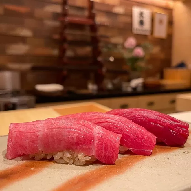 3 beautifully placed sushi rolls of rice with red raw fish on top
