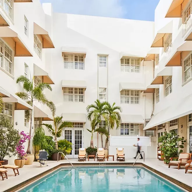Beautiful white building with a swimming pool in the middle and palm trees