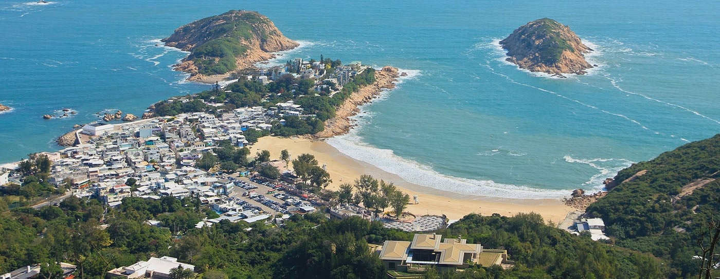 Birds eye view of small town and costal beach and blue sea at The Dragons Back coast