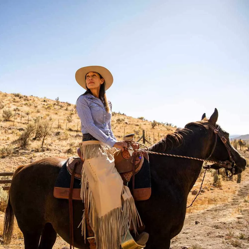 Women in country-western clothing and hat riding a horse in nature at The Lodge at Blue Sky, Utah