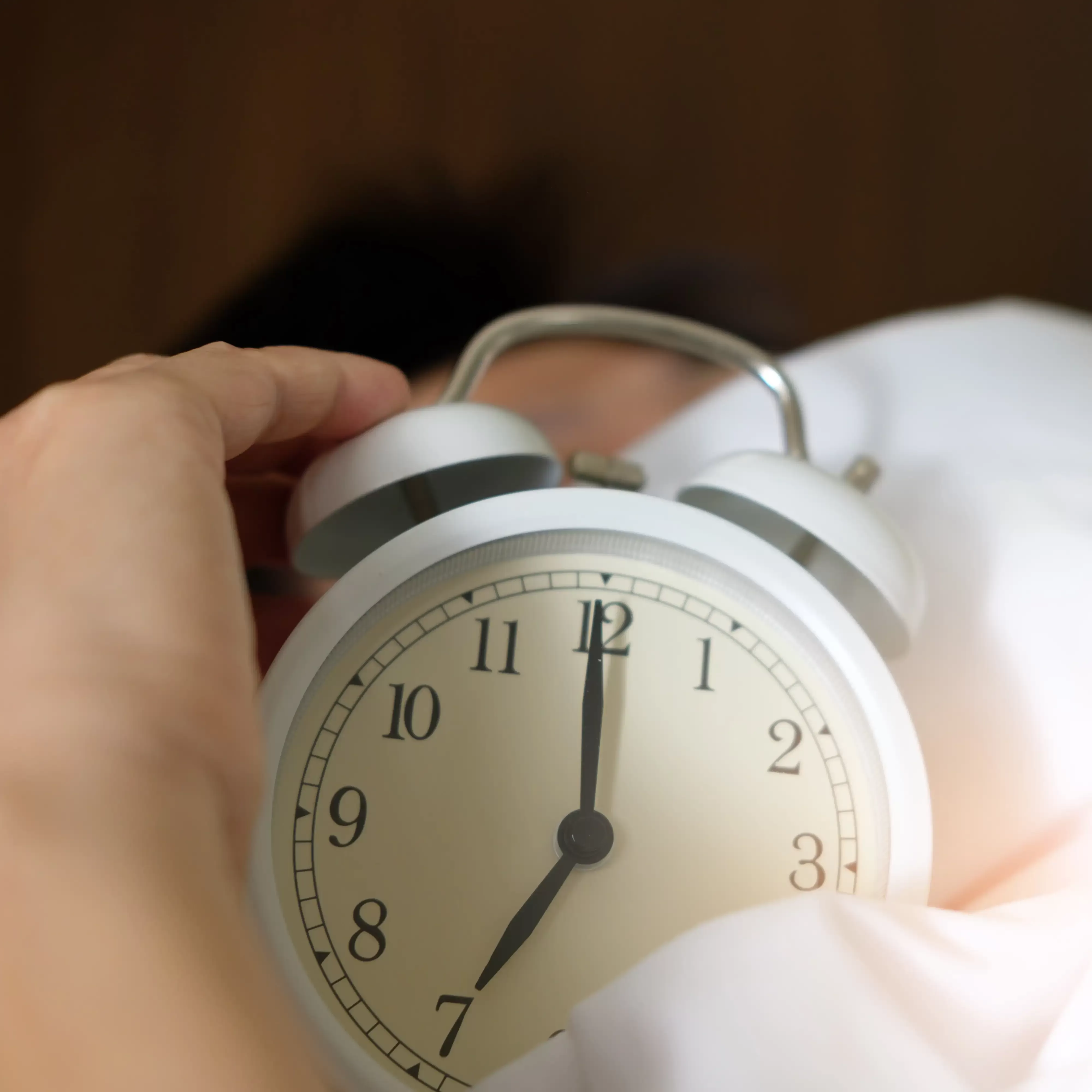 Hand holding white alarm clock