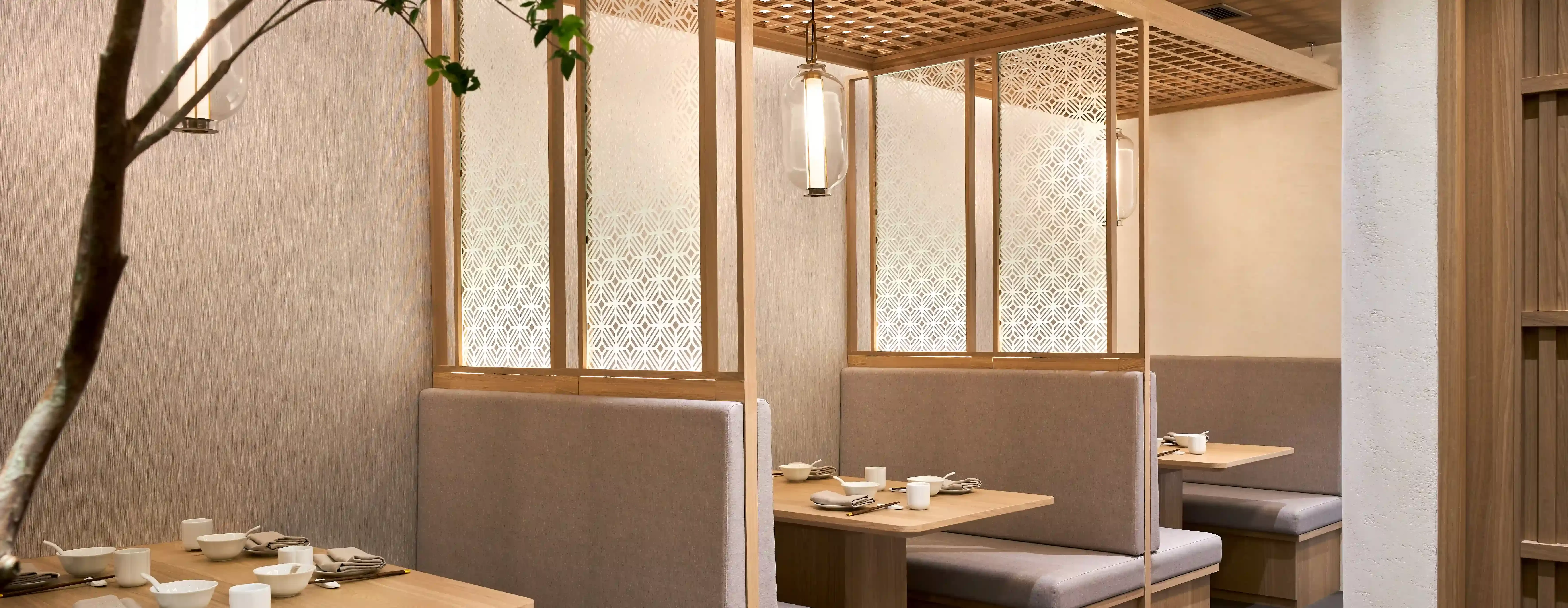 Simplistic interior wooden restaurant booths with a tree centre piece and grey cushion benches at Yue Bai, Singapore