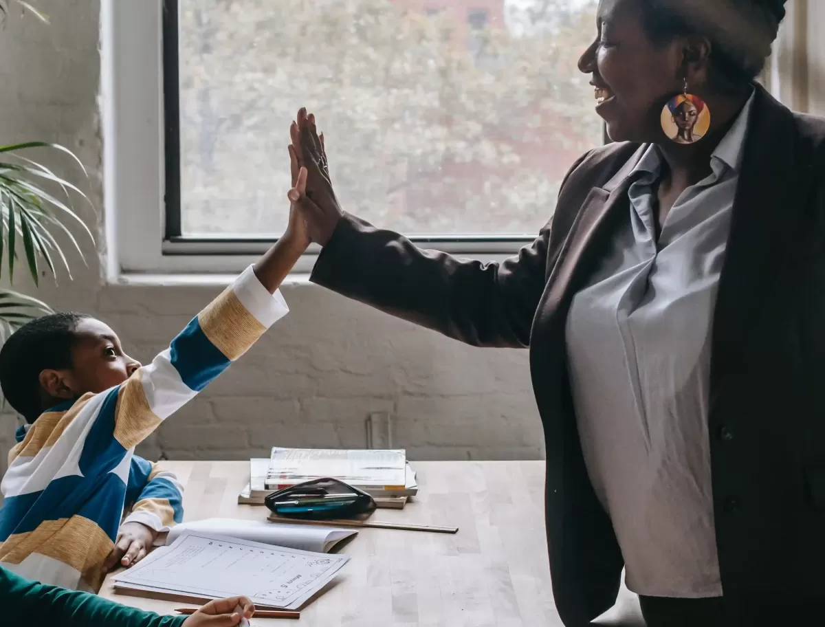 Teacher and student high fiving over desk