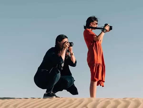 Two females taking photos on professional cameras whilst standing in the dessert stand.