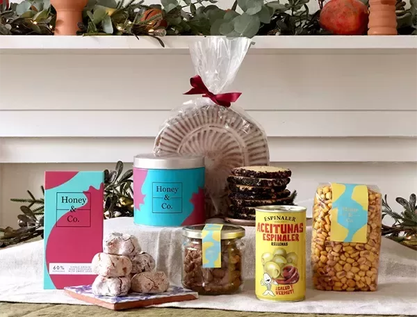 Food and drink laid out on the table surrounded by Honey Co House Party Hamper