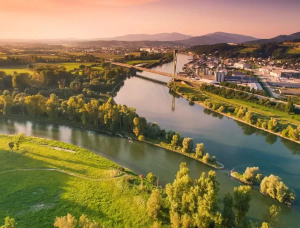 Stunning aerial view of the Isar River near Munich, showcasing lush greenery and scenic landscapes under a vibrant sunset sky.