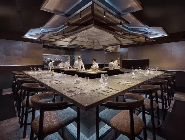 A spacious Dosa restaurant featuring a long table surrounded by chairs, inviting guests for a communal dining experience.