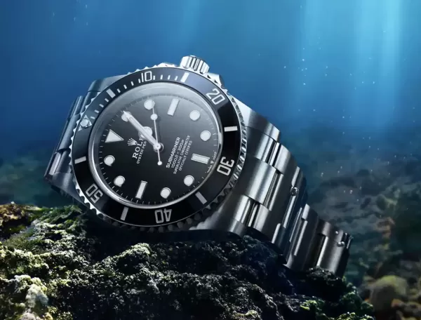 Rolex Submariner watch: Oystersteel - M124060-0001 sat in the bottom of sea on rocks