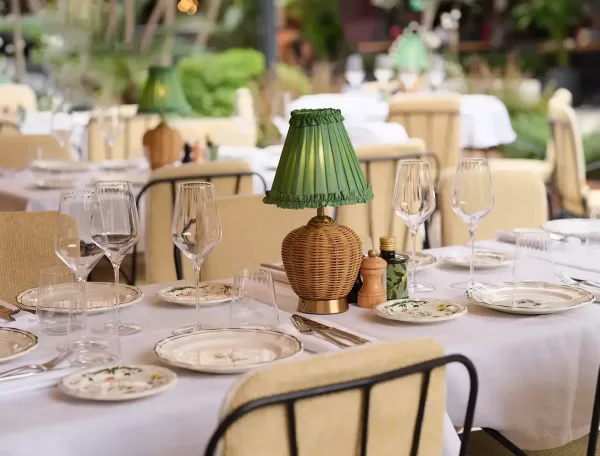 Elegant dining interior at Zeffirino restaurant in Monte Carlo, featuring exquisite cuisine and a stunning ambiance with china plates and green wicker lamp centrepiece.
