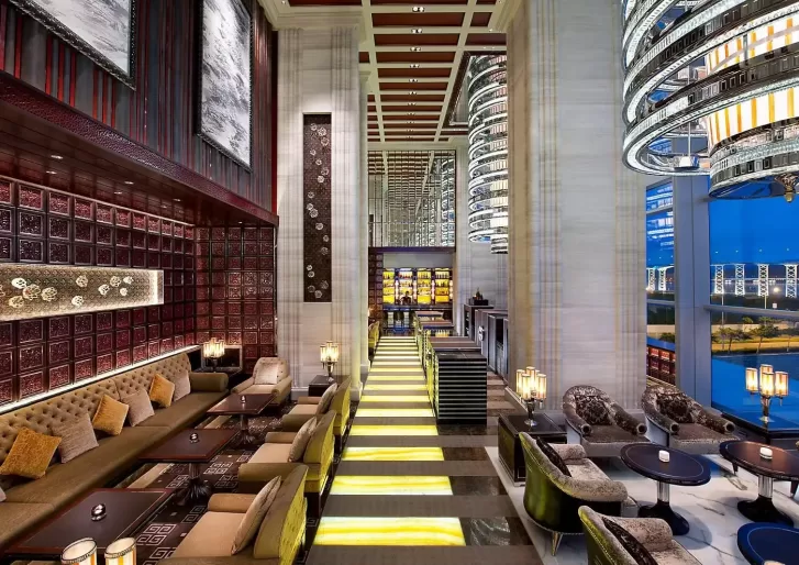 Beautiful spacious room at the Mandarin Oriental Macau with a bar on the right and sofas on the left and tall ceilings.