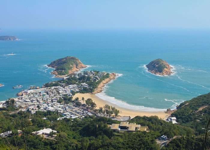 Birds eye view of small town and costal beach and blue sea at The Dragons Back coast