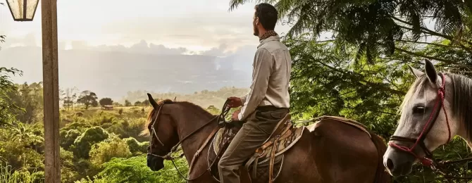 Men riding horse with a view of rainforest in Costa Rica