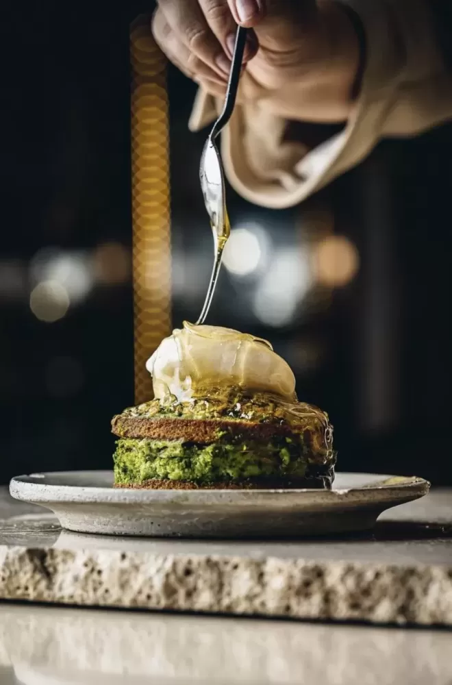 Person dribbling honey over plate of food