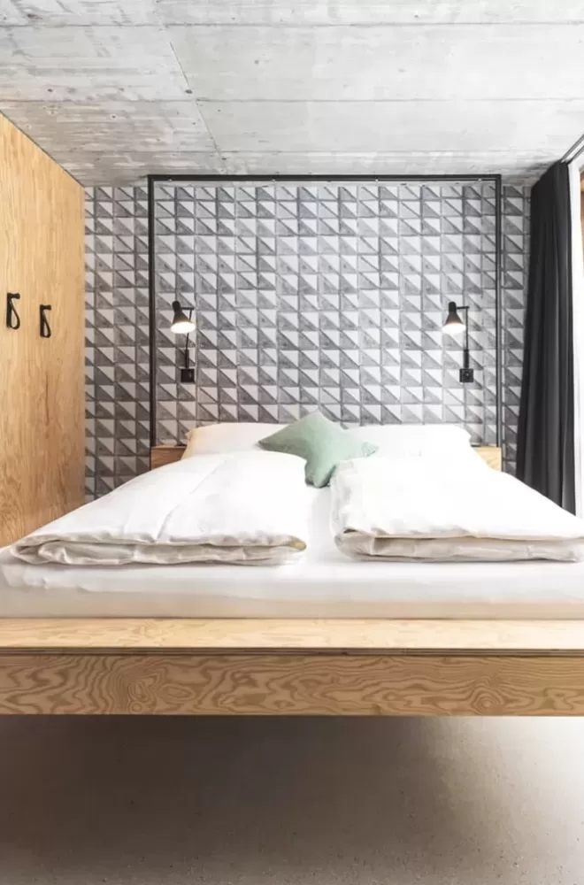 Wooden floating bed in front of tiled wall in hotel suite at Riders Hotel, Laax, Switzerland