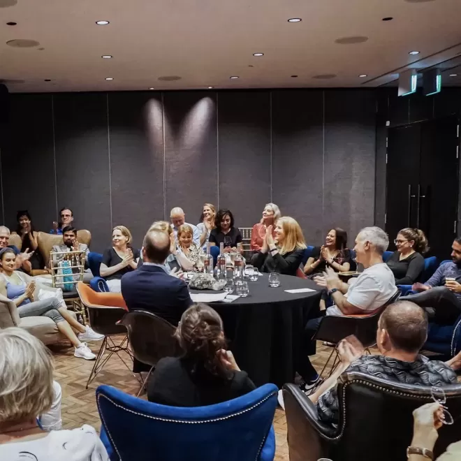 Meeting room filled with people sat down and clapping