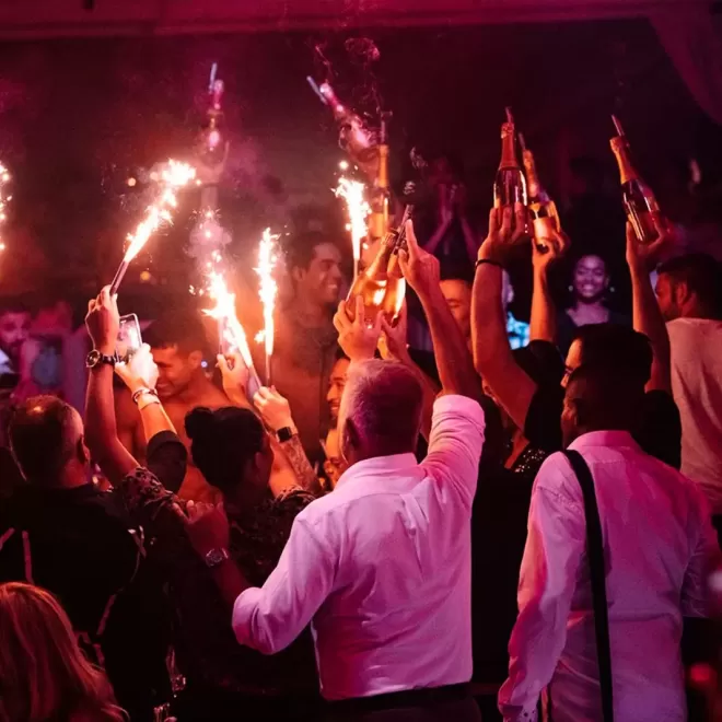 Group of people in a bar holding up sparklers