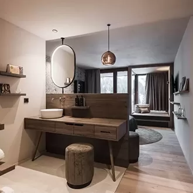 Inside luxury hotel suite, with wooden dressing table and stool at Hotel Badia Hill, Dolomites