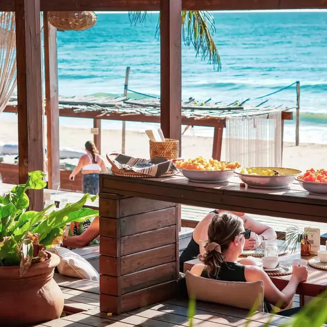 People sat eating lunch in a sea front wooden restaurant