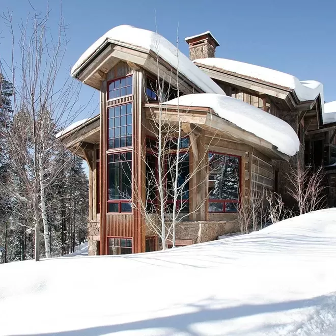 Exterior of Gold Mine Lodge sporting tall glass windows and snow on the roof in Colorado