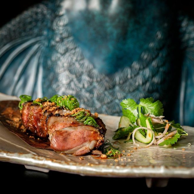 Luxurious display of meat cuisine and garnish in front of a blue fish sculpture