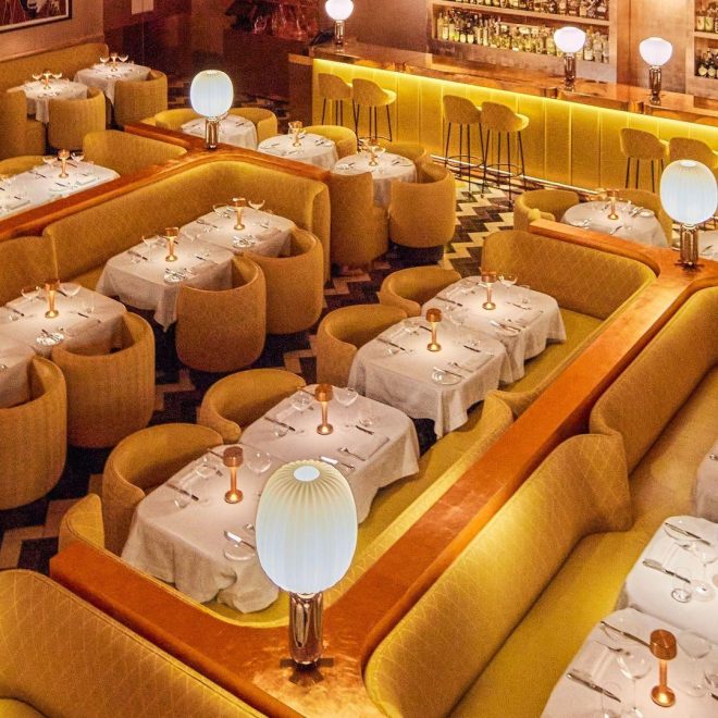 Birdseye view of yellow sofa and yellow rounded dining chairs with small white tables set up in rows in restaurant