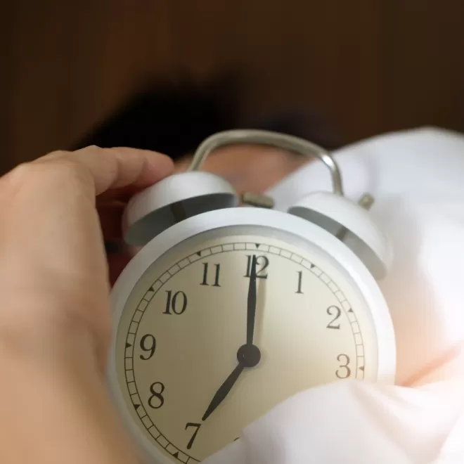 Hand holding white alarm clock