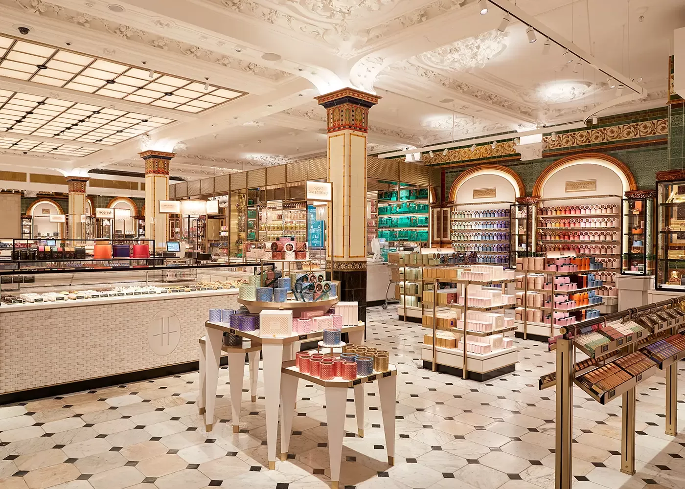 A luxurious, brightly lit store interior with ornate ceilings, tiled floors, and shelves displaying colorful boxes, perfumes, and beauty products. Decorative columns and elegant displays create an upscale shopping atmosphere.