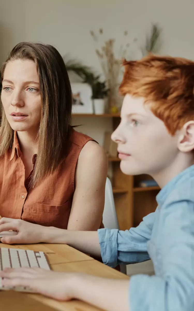 Women and boy sat at a desk on a computer